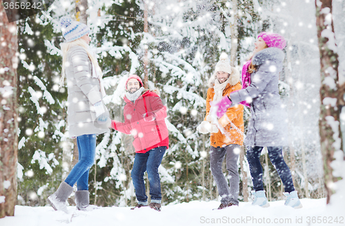 Image of group of happy friends playing snowballs in forest