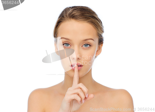 Image of beautiful young woman holding finger on lips