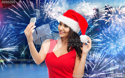 Image of woman in santa hat taking selfie by smartphone