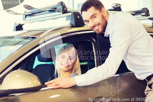 Image of happy couple buying car in auto show or salon