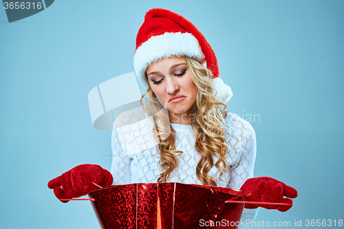 Image of Frustrated and annoyed beautiful young woman in Santa Claus hat