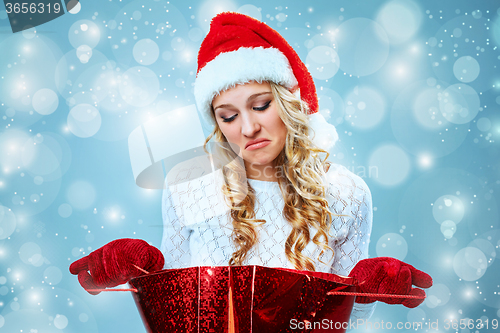 Image of Frustrated and annoyed beautiful young woman in Santa Claus hat