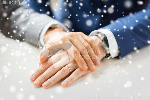 Image of close up of gay couple hands with wedding rings on