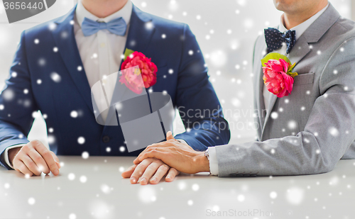 Image of close up of happy male gay couple holding hands