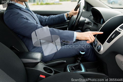 Image of close up of young man in suit driving car