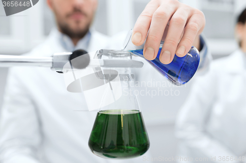 Image of close up of scientist filling test tubes in lab