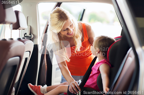 Image of happy mother fastening child with car seat belt