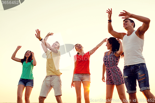 Image of smiling friends dancing on summer beach