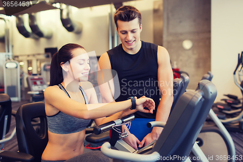 Image of happy woman with trainer on exercise bike in gym