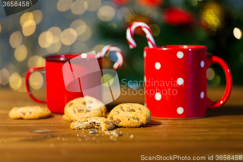 Image of christmas candy canes and cups on wooden table