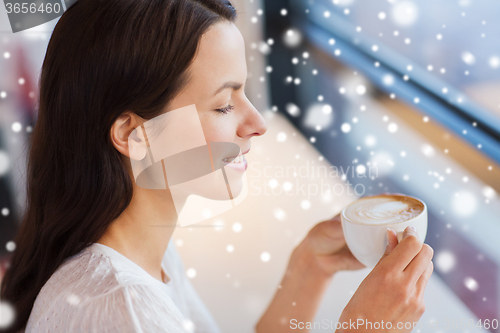 Image of smiling young woman drinking coffee at cafe