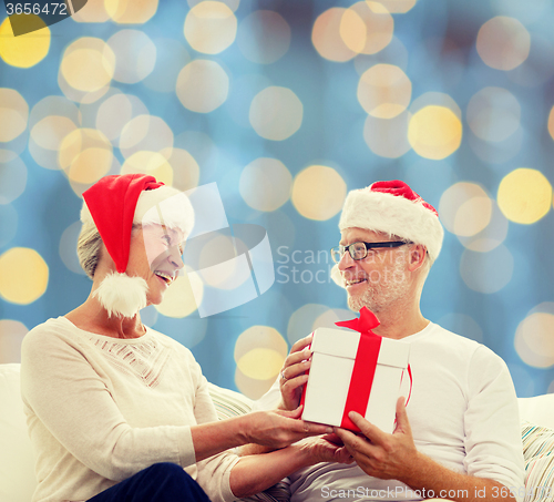 Image of happy senior couple with gift box at home