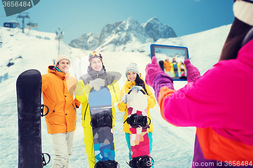 Image of happy friends with snowboards and tablet pc