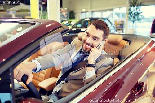 Image of happy man sitting in car at auto show or salon