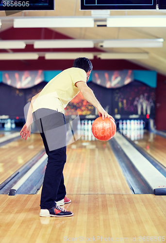 Image of happy young man throwing ball in bowling club