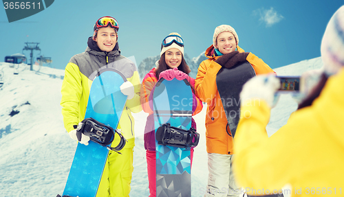 Image of happy friends with snowboards and smartphone