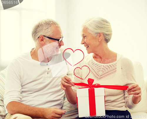 Image of happy senior couple with gift box at home