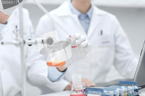 Image of close up of scientists filling test tube in lab