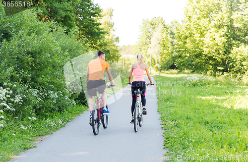 Image of happy couple riding bicycle outdoors