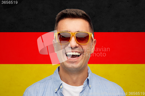 Image of face of smiling man in sunglasses over german flag