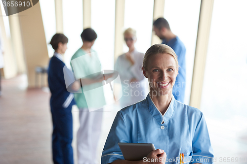 Image of female doctor with tablet computer  standing in front of team