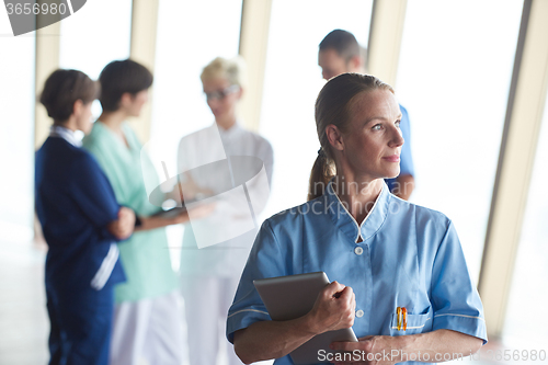 Image of female doctor with tablet computer  standing in front of team