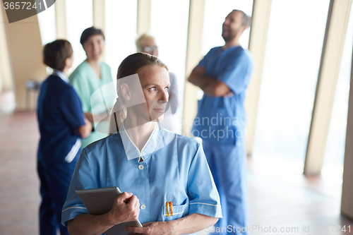 Image of female doctor with tablet computer  standing in front of team