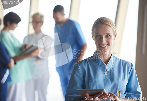 Image of female doctor with tablet computer  standing in front of team