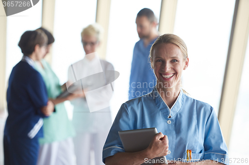 Image of female doctor with tablet computer  standing in front of team