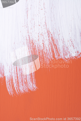 Image of Orange board being roughly painted with white paint