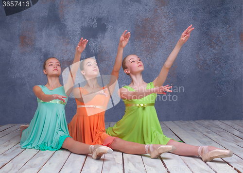 Image of Three young ballerinas posing on the floor 