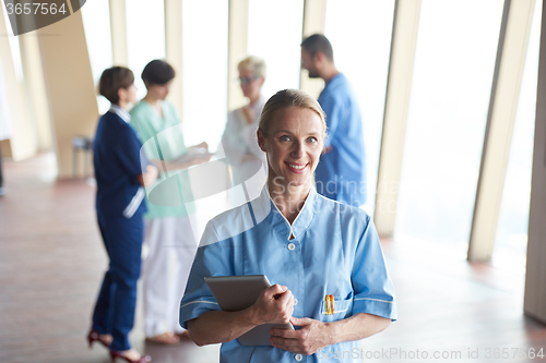 Image of female doctor with tablet computer  standing in front of team