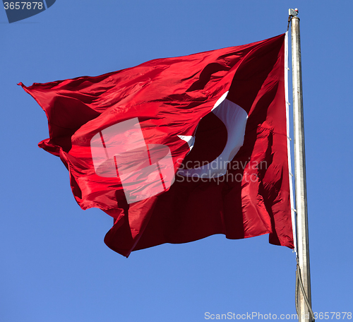 Image of Turkish flag on flagpole waving in wind