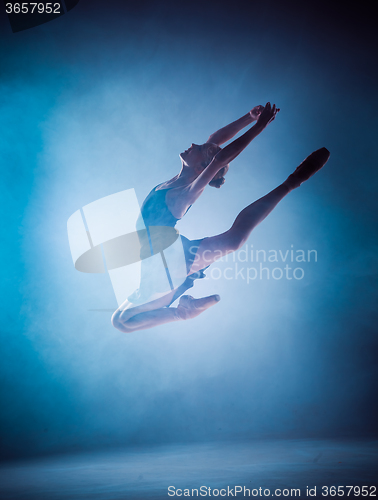 Image of The silhouette of young ballet dancer jumping on a blue backgrou