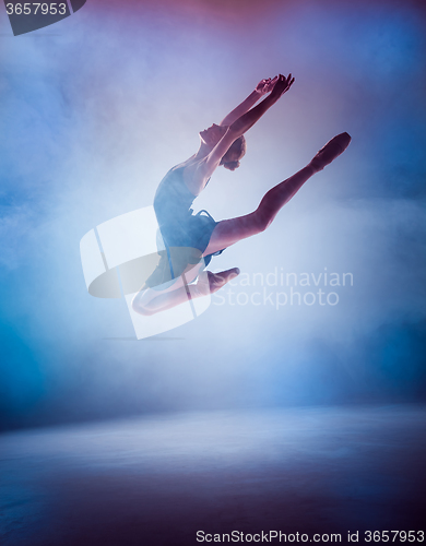 Image of The silhouette of young ballet dancer jumping on a blue backgrou