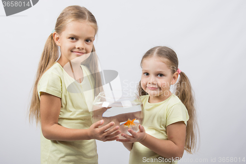 Image of Two girls holding hands in an aquarium with goldfish