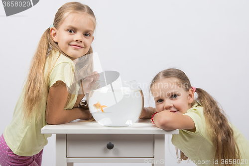 Image of Two girls have a small fishbowl with goldfish