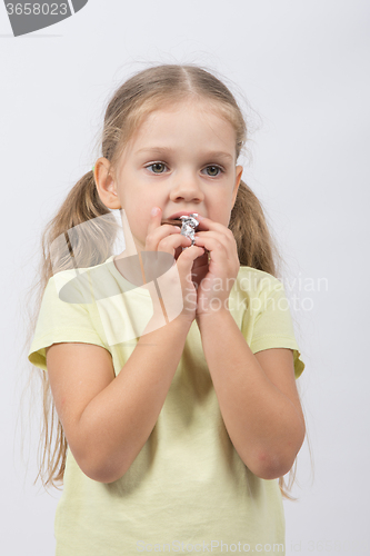 Image of The little girl eats a chocolate sweet tooth