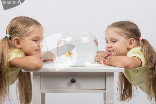 Image of Two girls looking at a goldfish in a small fishbowl