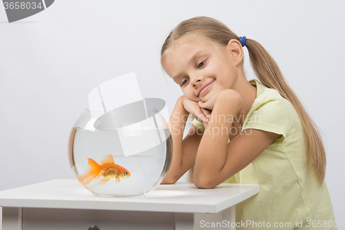 Image of Thoughtful girl dreaming and looking at goldfish