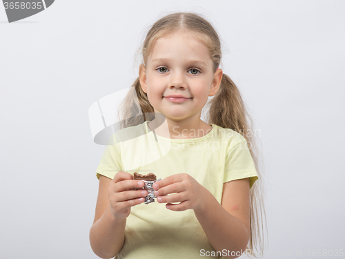 Image of Portrait of a four-year girl sweet tooth with chocolate in hand