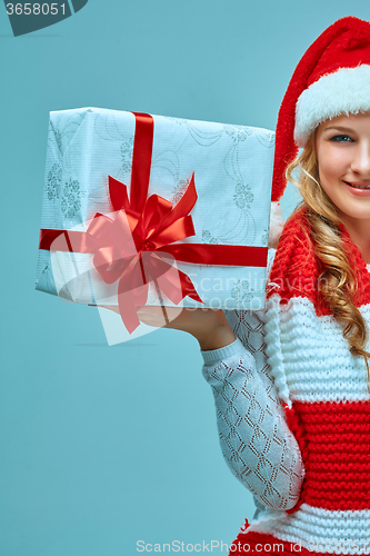 Image of Girl dressed in santa hat with a Christmas gift 