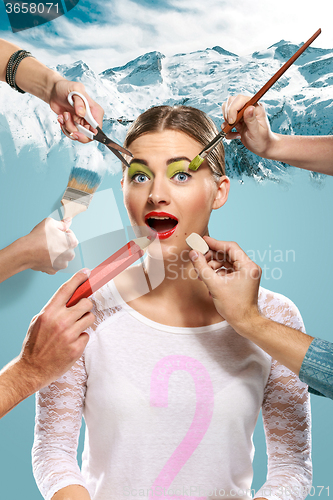 Image of The hands of visagists doing make-up young woman 