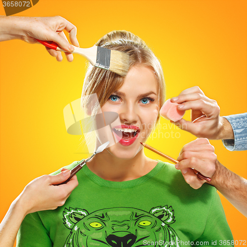 Image of The hands of visagists doing make-up young woman 