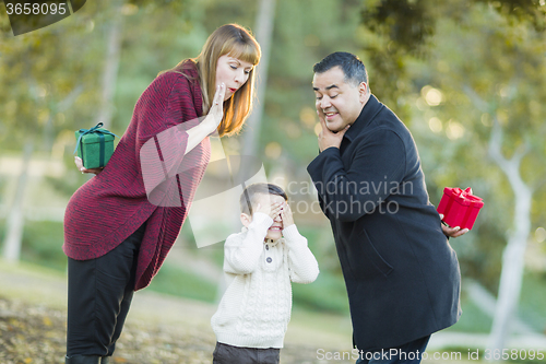 Image of Mixed Race Parents With Gifts for Young Boy Hiding Eyes