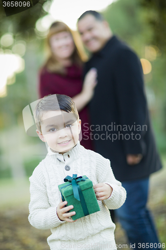 Image of Mixed Race Boy Holding Gift In Front with Parents Behind