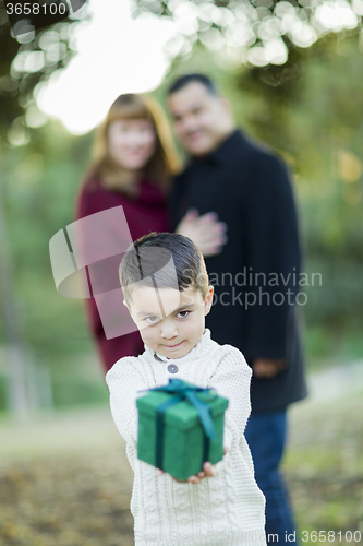 Image of Mixed Race Boy Holding Gift In Front with Parents Behind