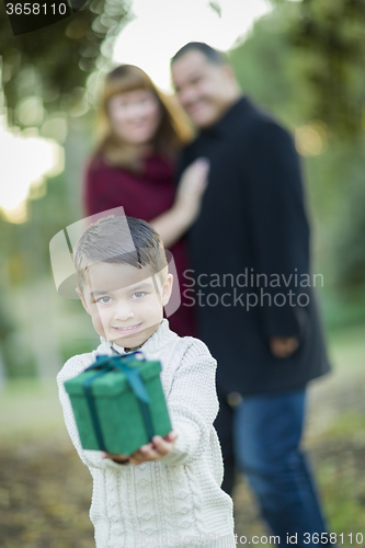 Image of Mixed Race Boy Holding Gift In Front with Parents Behind