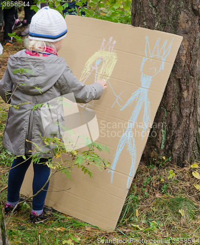 Image of Little girl drawing with crayons on cardboard