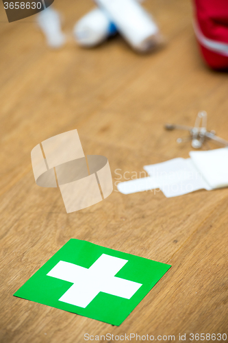 Image of First aid kit and green cross on a wooden surface